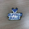 Product image of bright nickel pin with the words “Buffalo Bulls” in blue. Pin placed on oak wood surface.